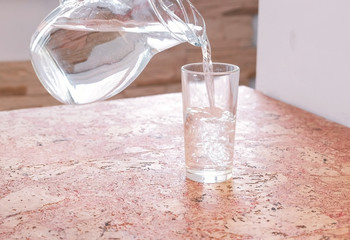 Pouring a water from decanter to glass and takes a glass.