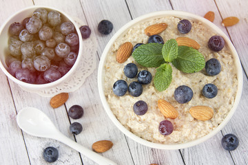 Oatmeal porridge.Breakfast cereals with blueberries and glass of milk on vintage white wooden table.Healthy eating