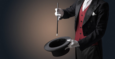 Illusionist white hand wants to conjure with magic wand from a black cylinder something
