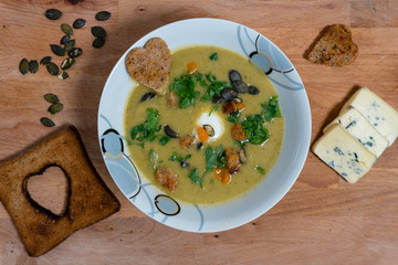 homemade cream broccoli soup. wooden background, croutons, blue cheese and hearts of toasted bread for decoration.Top view