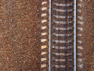 Railway top view. Old railroad, part of rail track for trains. Iron rails and concrete sleepers, stony ground, brown rubble
