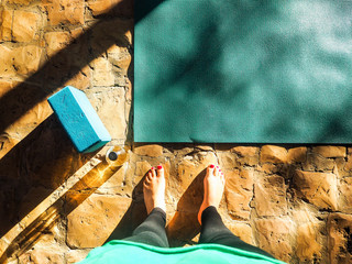 legs of a mindful woman startinh practise  yoga on a mat outdoors in the jungle with bird view
