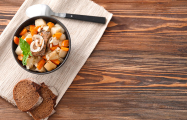 Bowl with tasty meat and potatoes on table
