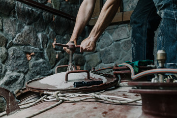 Hands unscrew screw lock of  big tank hatch
