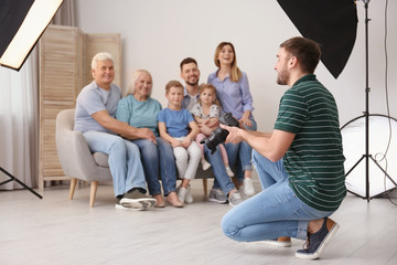 Professional photographer taking photo of family on sofa in studio