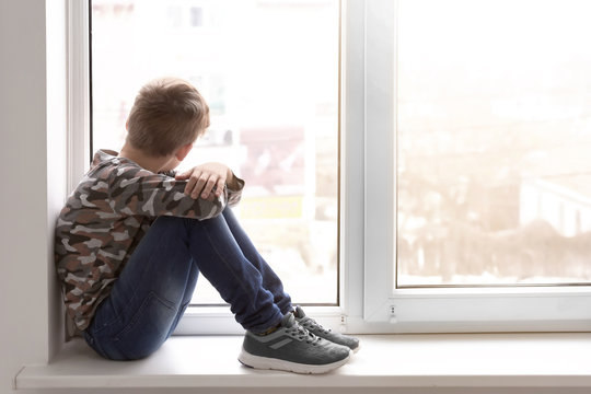 Lonely little boy near window indoors. Child autism