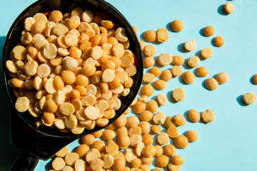 split peas spilled from wooden spoons on a blue background