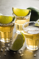 Macro photo of shots of gold Mexican tequila with lime and salt on wooden rustic background....