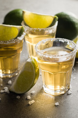 Macro photo of shots of gold Mexican tequila with lime and salt on wooden rustic background. Alcoholic drink concept. selective focus.