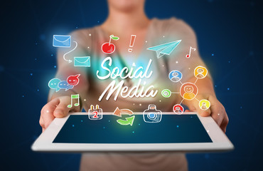 Casual young woman holding tablet with social media icons