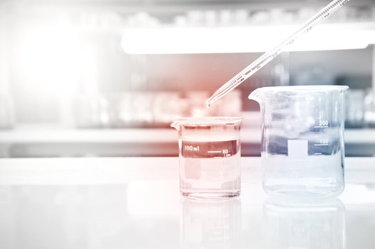 glass beaker with drop water of pipette in medical science laboratory background