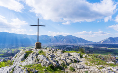 A steel cross on top of the mountain. sky and rays of the sun. Beautiful landscape.