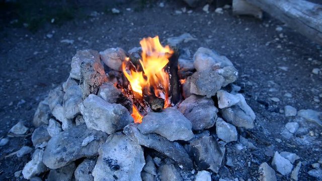 Bonfire in a camp-fire of stones outdoors at dusk