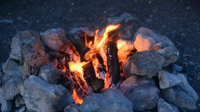 Bonfire in a camp-fire of stones outdoors at dusk