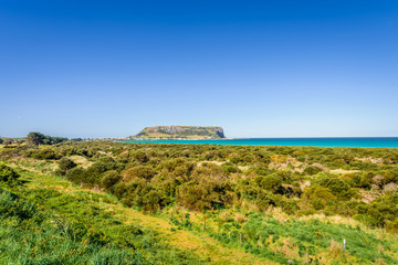 Fototapeta na wymiar Stunning view point to big old volcanic rock mountain top called The Nut with blue turquoise water beach bay and green grass lands on warm sunny clear sky day, Stanley, North-West, Tasmania, Australia