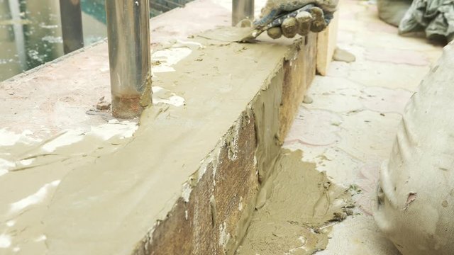 spatula and bucket with mortar on the construction site. the builder finishes the surface with plaster. 4k. pool repair.