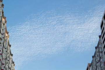 Fototapeta na wymiar City blue sky with shallow clouds and houses on each side.