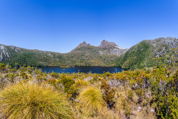 Pretty view to great deep blue mountain lake and green orange shore jungle forest bush land on warm...