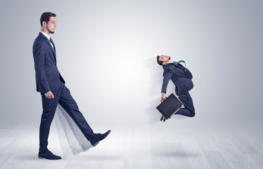 Big man in suit kicking out little himself with simple white wallpaper
