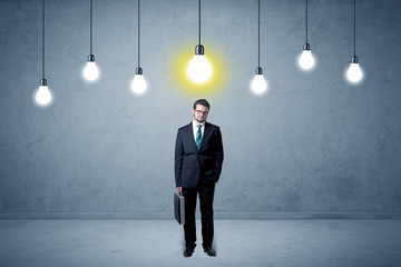 Fototapeta premium Handsome businessman in an empty space with bulbs above and uninspired face 