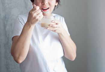 Happy woman eating muesli or porridge for breakfast, the concept of a healthy diet and detox.