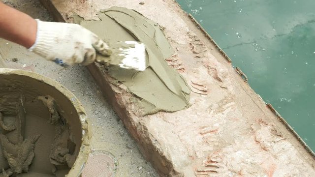 spatula and bucket with mortar on the construction site. the builder finishes the surface with plaster. 4k. pool repair.