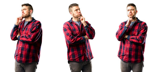 Young man thinking and looking up expressing doubt and wonder isolated over white background,...