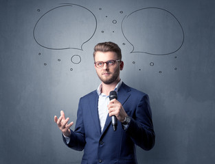 Businessman speaking into microphone with speech bubbles over his head