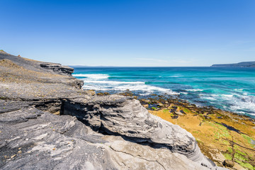 Fototapeta na wymiar Amazing view to stunning rocky sandy beach deep blue water of southern ocean antarctica on warm sunny day with blue sky after hiking on to South Cape Bay, South-West National Park, Tasmania, Australia