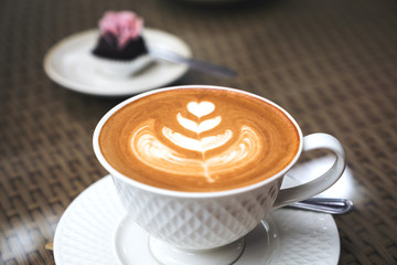 A piece of snack and a latte coffee cup on table in cafe