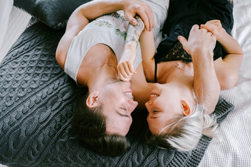 Lovely couple together at home. Pretty woman and attractive man wearing home clothes clothes sitting on a bed and hugging.