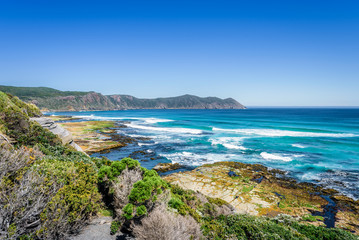 Amazing view to stunning rocky sandy beach deep blue water of southern ocean antarctica on warm sunny day with blue sky after hiking on to South Cape Bay, South-West National Park, Tasmania, Australia