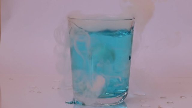 The blue water in glass and put dry ice inside and engender white smoke on white background.
