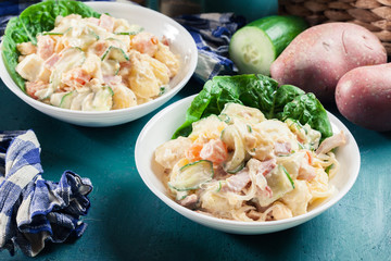 Delicious potato salad with ham, egg and cucumber