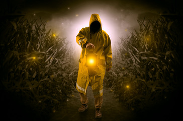 Fototapeta premium Man in raincoat at night coming from thicket and looking something with glowing lantern 
