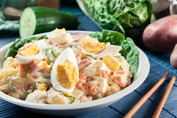 Delicious potato salad with ham, egg and cucumber
