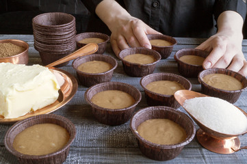 Women's hands preparing homemade chocolate cupcakes.