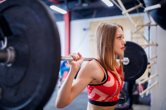 Photo of sports woman squatting with bar