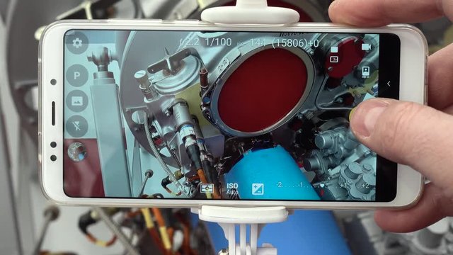 A man engineer photographs a jet engine. The man's hand takes a picture of the engine of the aircraft, using a modern smartphone and a monopod for selfie.