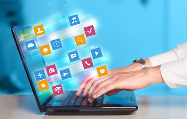 Hand using laptop with colorful fast moving application icons and symbols concept
