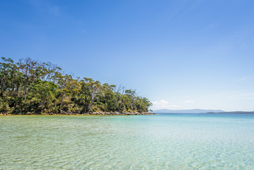 Amazing view to small paradise like island sandy beach with turquoise blue water and green shore jungle forest on warm sunny clear sky day camping ground, Jetty Beach Bruny Island, Tasmania, Australia