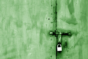 Old padlock on metal gate in green tone.