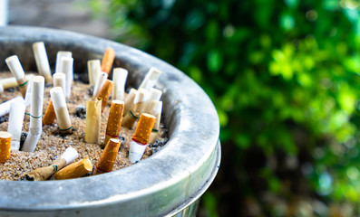 Non smoking world concept. Cigarettes in ashtray at smoking area. Cigarettes and tobacco inside box ash tray on the outdoor tabl