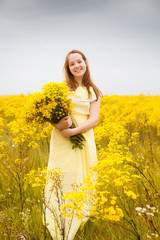 Naklejka na ściany i meble young girl walking in field with flowers.