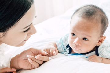 Baby hand holding finger mother on white bed.Love of family concept