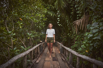 Traveling girl on the wooden bridge. Pretty young woman in the jungle. Summer lifestyle and adventure photo