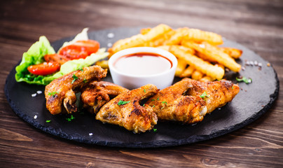 Grilled chicken wings, chips and vegetables