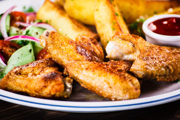 Grilled chicken wings, chips and vegetables