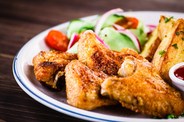 Grilled chicken wings, chips and vegetables