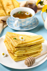 Stack of thin pancakes crepes for breakfast with honey and tea